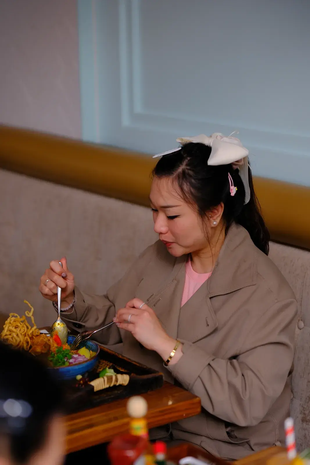 A guest eating from a colourful noodle bowl at a table by the wall