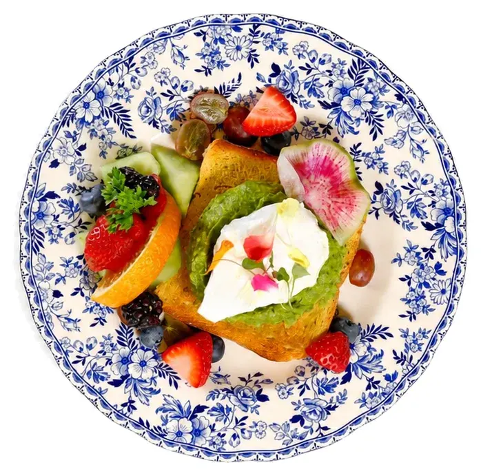 A pastry with fresh fruit, cream and edible flowers on a blue-and-white patterned plate