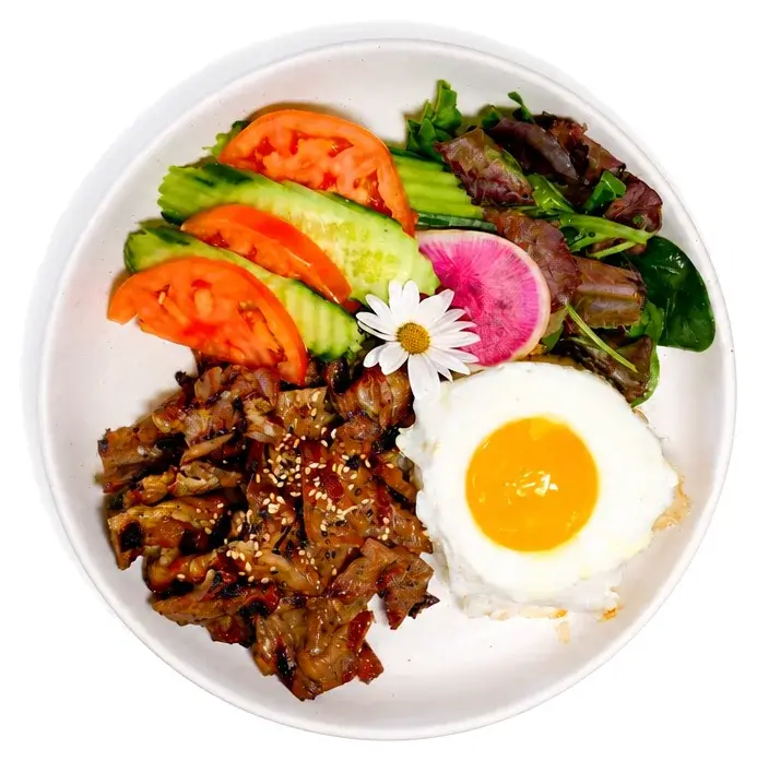 Grilled beef with rice, a fried egg, avocado and tomato